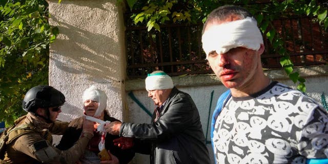 People receive medical treatment at the site of the Russian bombing, in Kyiv, Ukraine, October 10, 2022. 